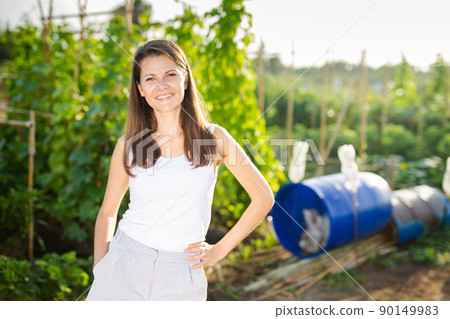 Portrait of smiling contented young woman in garden on sunny day 90149983