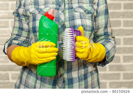 Woman in protective glove with bottle of detergent. Woman in protective glove with bottle of detergent. 90150926