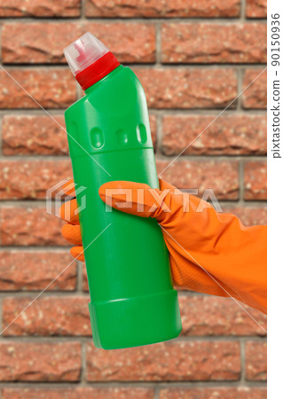 Woman's hand in protective glove with bottle of washing liquid. Woman's hand in protective glove with bottle of washing liquid. 90150936