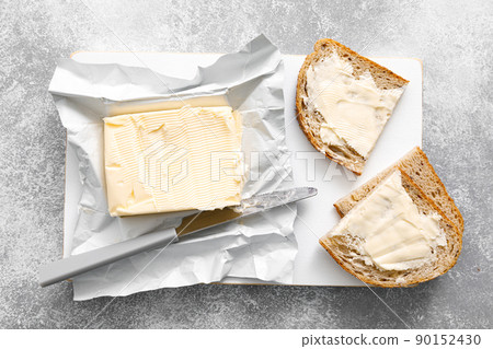 Block of butter with butter knife in a open pack.  Buttering bread 90152430