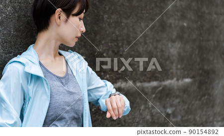 A woman in sportswear leaning against a wall 90154892