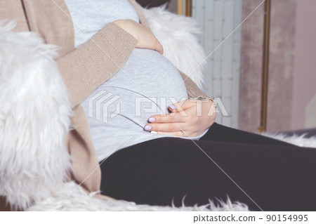 Pregnant woman holding belly. Sitting in chair. Pregnant woman holding belly. Sitting in chair. 90154995