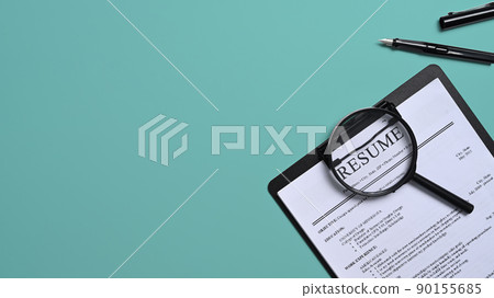 Top view resumes of applicants and magnifying glass on green background. Job search concept Top view resumes of applicants and magnifying glass on green background. Job search concept 90155685