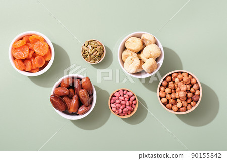 Mix of dried fruits and nuts in bowls - symbols of judaic holiday Tu Bishvat. green background 90155842