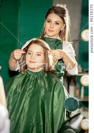 Professional hair care. Beautiful young caucasian brunette woman with long hair receiving hairstyling in a beauty salon Professional hair care. Beautiful young caucasian brunette woman with long hair receiving hairstyling in a beauty salon 90156370