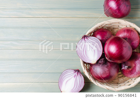 Red onions in a wicker basket. Fresh harvest. Light wood background Red onions in a wicker basket. Fresh harvest. Light wood background 90156841