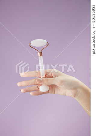 Front view of using cosmetic roller on hand in purple background for cosmetic advertising Front view of using cosmetic roller on hand in purple background for cosmetic advertising 90156952