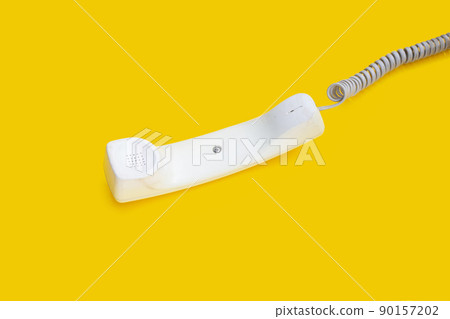 Handset of landline phone on yellow background. 90157202