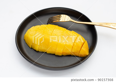 Yellow mango slices in black plate on white background. Yellow mango slices in black plate on white background. 90157308