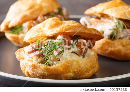 Profiteroles with forest mushrooms, cream and herbs close-up in a plate. horizontal 90157388