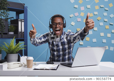 Overjoyed smiling call center operator showing thumbs up gesture with hands while looking at camera. Happy cheerful customer support representative indicating that client problem is solved. Overjoyed smiling call center operator showing thumbs up gesture with hands while looking at camera. Happy cheerful customer support representative indicating that client problem is solved. 90158774