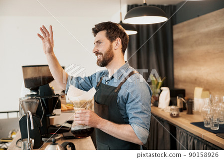 Barista joyfully greets a loyal customer while holding a ready-made coffee filter  90158926