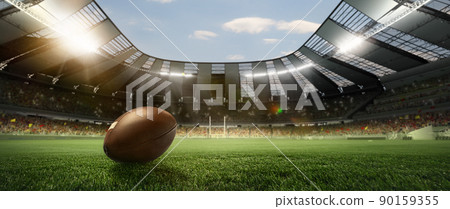 Leather american football ball on grass of football field at stadium with spotlight. Concept of sport, art, energy, power 90159355