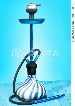 Blue hookah with black rubber tube and blue and white flask on light blue background. 90160045