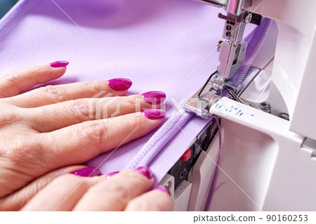 Woman overstitches a dress on an overlocker 90160253