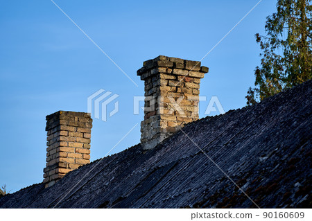 An old brick chimney against the blue sky. An old brick chimney against the blue sky. 90160609
