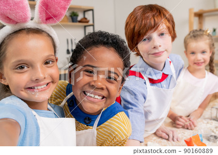 Cute boy and his mother rolling dough while cooking homemade pastry by table in the kitchen 90160889