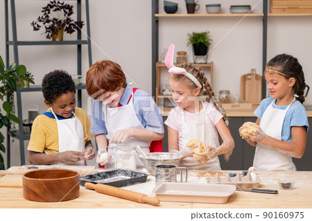 Adorable little sisters looking at camera with wide smiles while standing at wooden table and preparing healthy snack for their parents 90160975