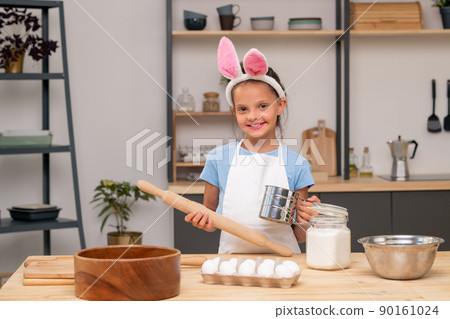 Close-up shot of little girl searching for salad recipe on digital tablet while standing at wooden kitchen table Close-up shot of little girl searching for salad recipe on digital tablet while standing at wooden kitchen table 90161024