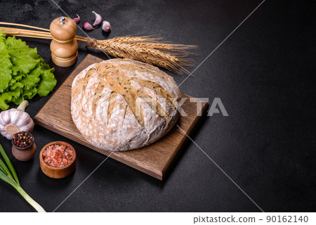 White round bread with flax seeds on a cutting board White round bread with flax seeds on a cutting board 90162140