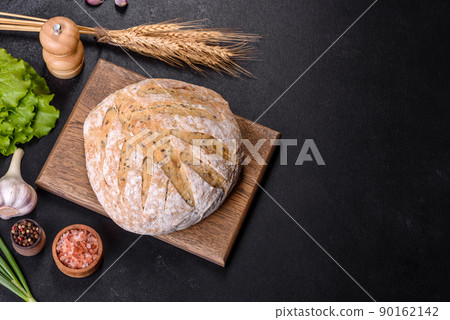 White round bread with flax seeds on a cutting board White round bread with flax seeds on a cutting board 90162142