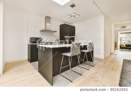 The interior of a cozy kitchen with a breakfast bar and modern equipment in dark colors in a residential apartment 90162892