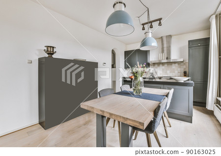 Home interior design of modern loft apartment with open kitchen in minimalist style and dining zone with table and chairs 90163025