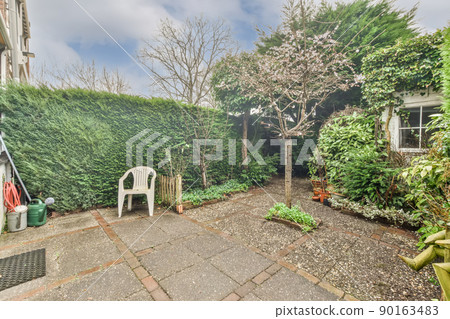 Cozy backyard with lots of plants and tiled floors at the modern cottage 90163483