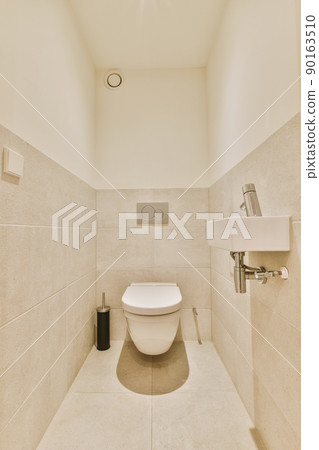 The interior of a bathroom with a hinged toilet and a ceramic sink in a modern house 90163510