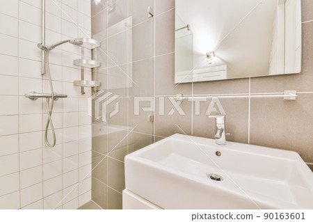 Sinks with mirrors and shower box with glass door in modern bathroom with white tiled walls Sinks with mirrors and shower box with glass door in modern bathroom with white tiled walls 90163601