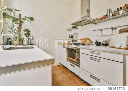 Well organized small home kitchen interior with sink againts light furniture with stove and oven in urban apartment Well organized small home kitchen interior with sink againts light furniture with stove and oven in urban apartment 90163713