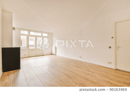 Interior of spacious light room with fireplace and elegant chandelier against balcony door and windows Interior of spacious light room with fireplace and elegant chandelier against balcony door and windows 90163969