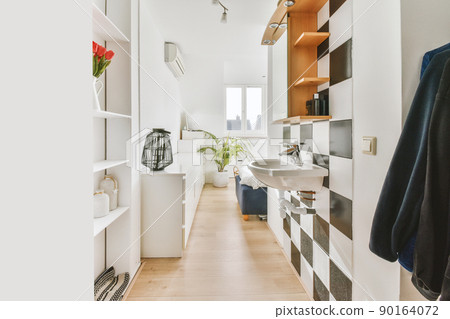 A small room with lots of shelves, a sink and wooden floors in a modern house 90164072