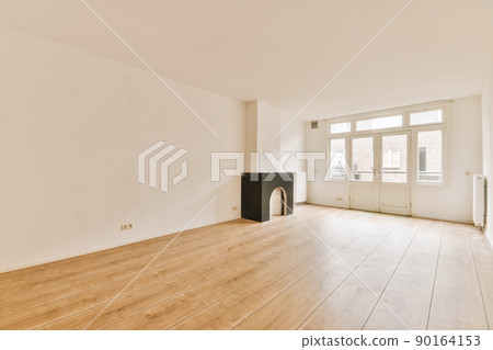 Interior of spacious light room with fireplace and elegant chandelier against balcony door and windows 90164153