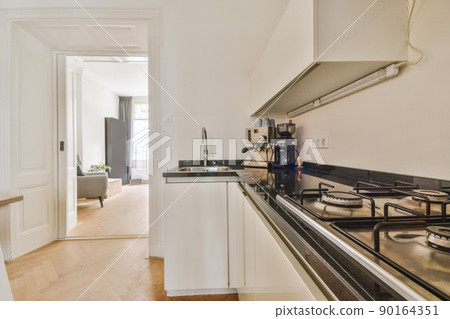 Kitchen in a modern house with white cabinets and appliances in metal color 90164351