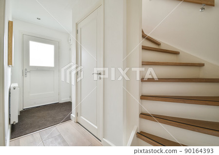 Closed white door of room located near framed pictures and stylish lamp on top of stairway at home Closed white door of room located near framed pictures and stylish lamp on top of stairway at home 90164393