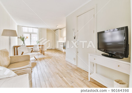 Contemporary open plan kitchen with dining table set and gray sofa in light spacious room Contemporary open plan kitchen with dining table set and gray sofa in light spacious room 90164398