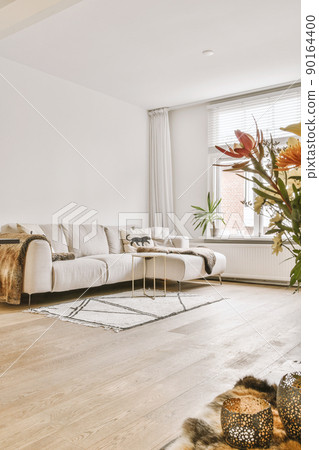 Comfortable couch located near carpet and table against window and sofa with TV in spacious minimalist style living room in modern apartment 90164400