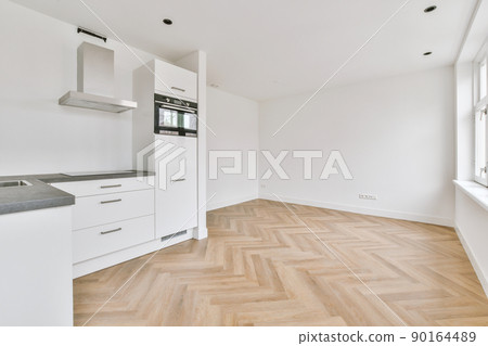 Corner of modern kitchen with white walls, wooden floor and empty room 90164489