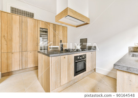 The interior of a spacious, bright kitchen with wooden furniture in a modern house The interior of a spacious, bright kitchen with wooden furniture in a modern house 90164548
