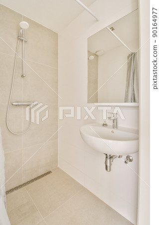 Sink with tap,shower box, and liquid soap hanging on tiled wall under mirror in contemporary restroom at home 90164977