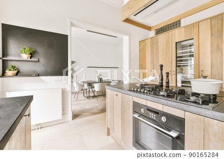 The interior of a spacious, bright kitchen with wooden furniture in a modern house The interior of a spacious, bright kitchen with wooden furniture in a modern house 90165284