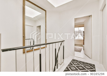 The second floor of a residential building with a large square mirror above the stairs 90165294