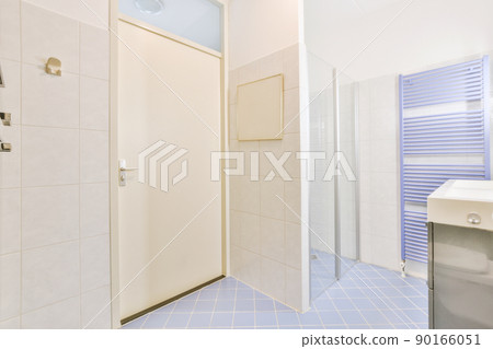 Bathroom interior with white and blue tiles and ceramic sink and glass shower cabin in a modern apartment 90166051