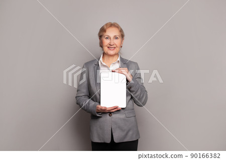 Happy middle aged senior lady holding digital tablet with empty display and smiling 90166382