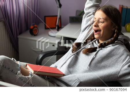 A young girl yawns during a break in her school reading. A young girl yawns during a break in her school reading. 90167094