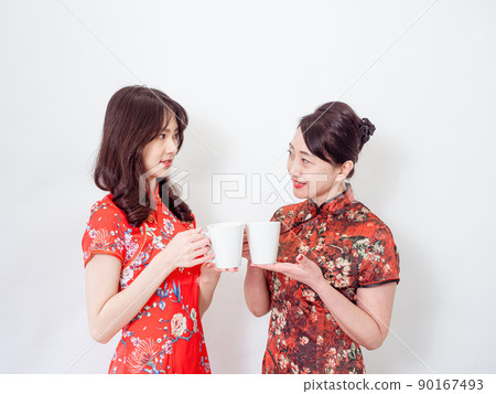 Portrait of mature asian mother and her asian daughter both wearing traditional cheongsam qipao dress relaxing drinking on white background. Portrait of mature asian mother and her asian daughter both wearing traditional cheongsam qipao dress relaxing drinking on white background. 90167493