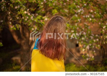 Yellow and blue fabric on the girl. Teen girl is standing with the Ukrainian flag. Yellow and blue fabric on the girl. Teen girl is standing with the Ukrainian flag. 90167585