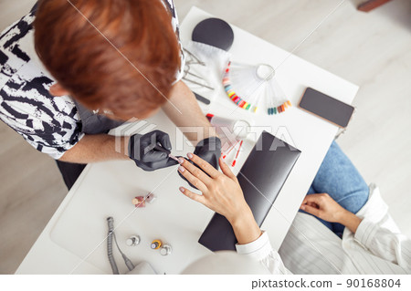 Proffesional manicure master working on nails in salon 90168804