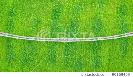 Winding asphalt road over fields of green grass. Aerial minimalistic backdrop 90169409